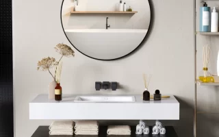 Round bathroom mirror above modern vanity with black cabinet