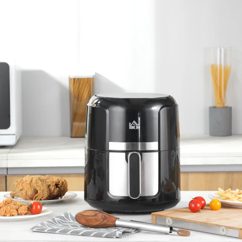 Compact black air fryer with preset cooking options, fries, and chicken placed nearby.
