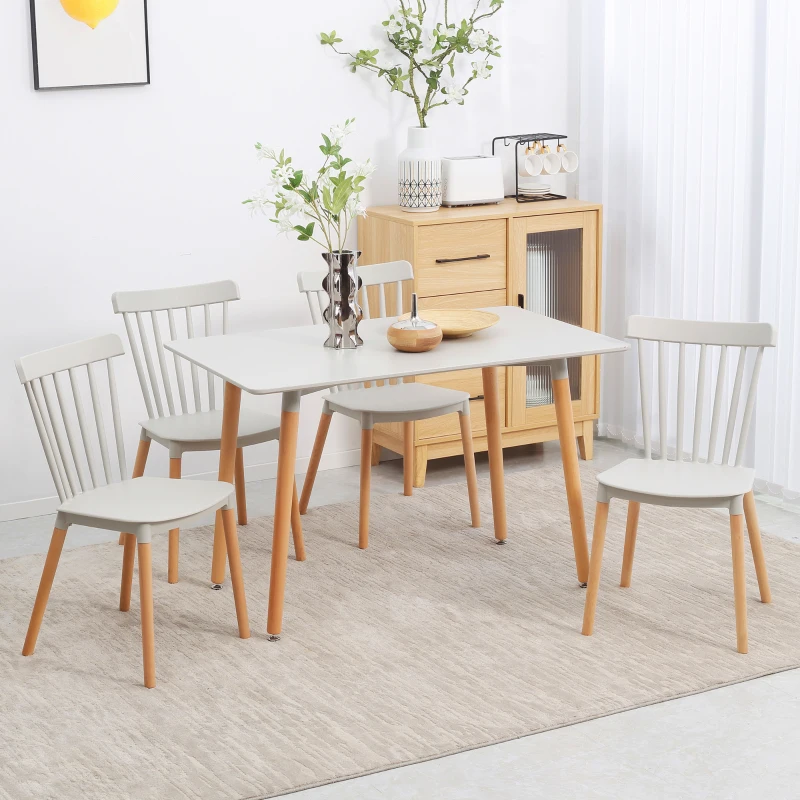 Scandinavian style dining table with four light wood chairs in bright living space.
