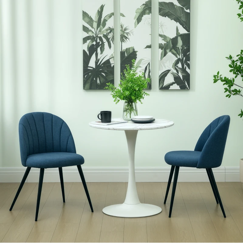 Pair of blue velvet dining chairs beside small round white table in modern room.
