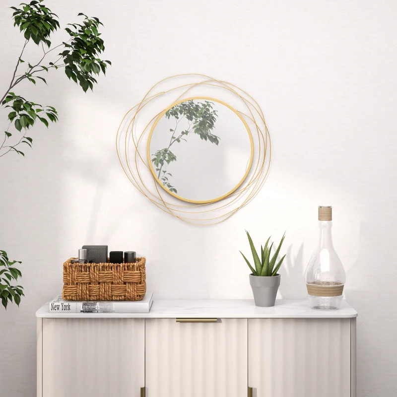 Round gold frame mirror above white cabinet with décor accents
