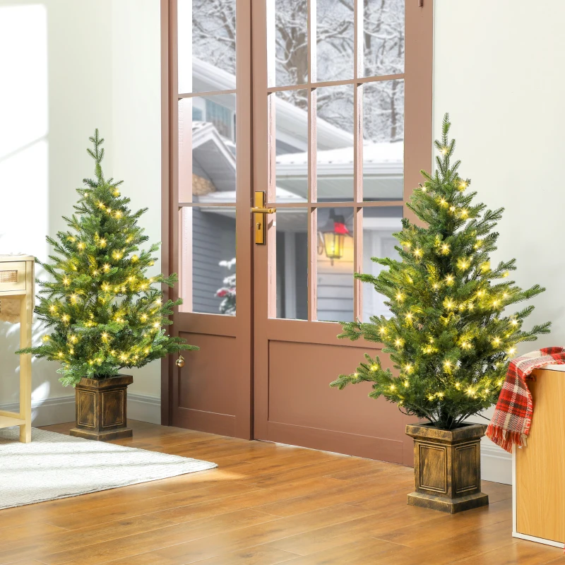 Pair of small lit Christmas trees near glass doors.