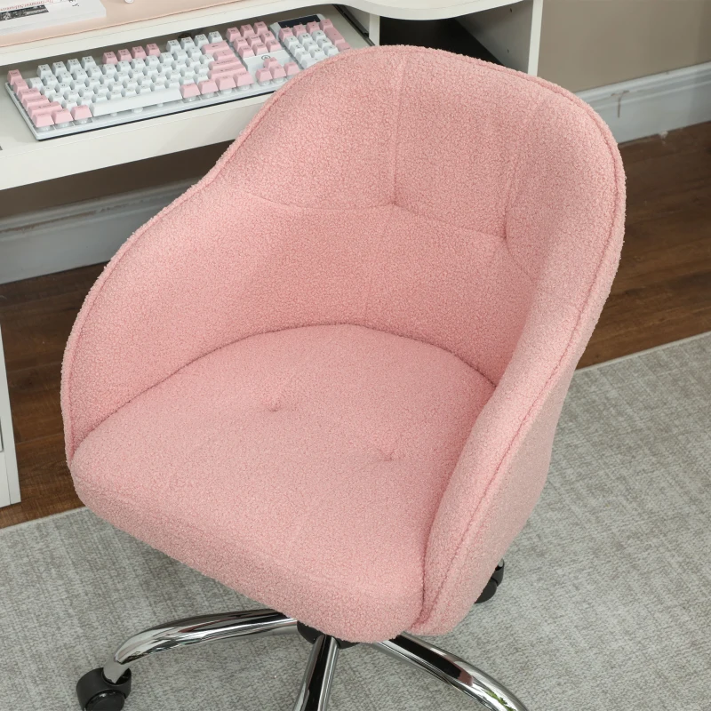 Pink boucle swivel chair beside computer desk and keyboard
