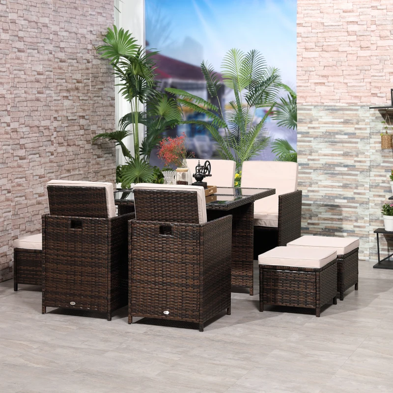 Brown rattan cube dining set with glass-top table and beige cushions indoors.
