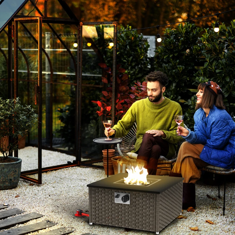 Couple relaxing beside a rattan gas fire table in garden.