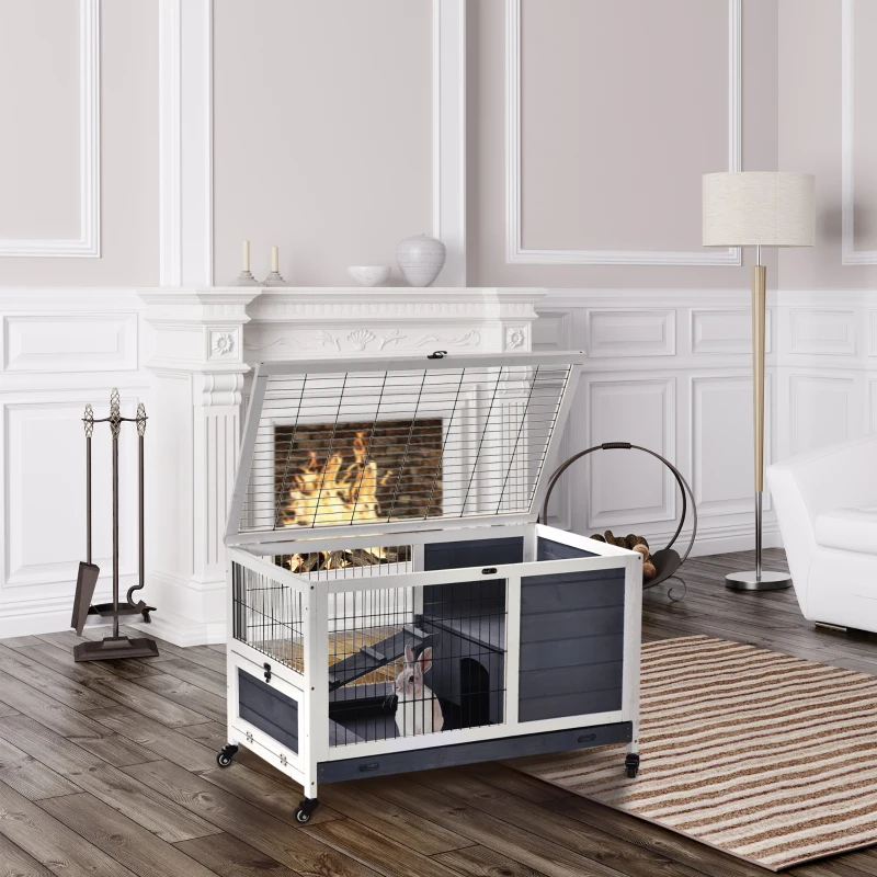 Indoor rabbit hutch with open top, wheels, and a rabbit inside near a fireplace.
