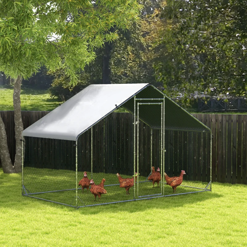Tall metal chicken run with shade cover and chickens feeding in grassy yard.
