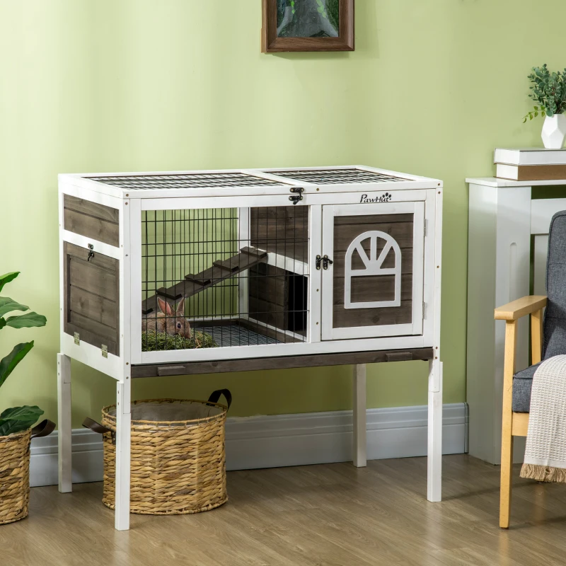 Two-level indoor rabbit hutch with ramp and wire panels on wooden floor.
