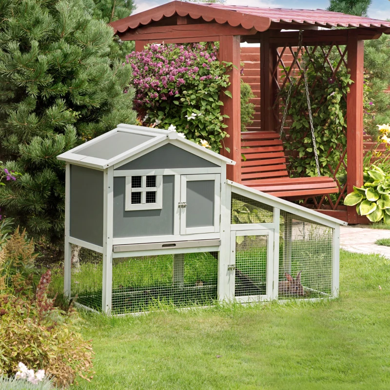 Grey rabbit hutch with sunlight roof and side run in a garden.
