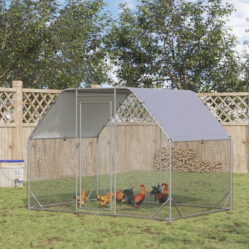 Metal walk-in chicken run with shade cover and hens roaming on grass.
