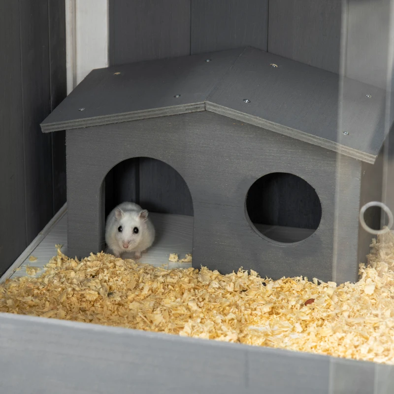 Close-up of white hamster in a cozy gray wooden hut on bedding.

