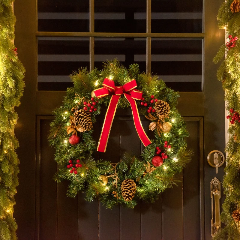 Glowing Christmas wreath with red bow hanging on door.