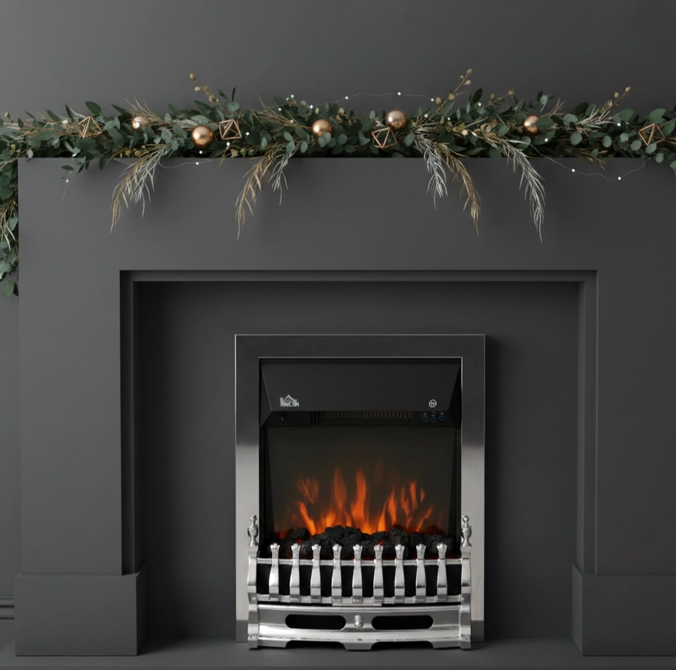Minimal green garland with metallic ornaments on grey mantel.